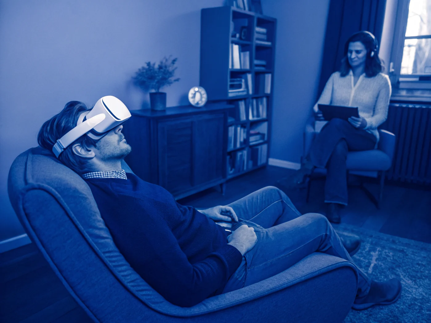 A patient in a VR headset during a therapy session while the clinician observes attentively